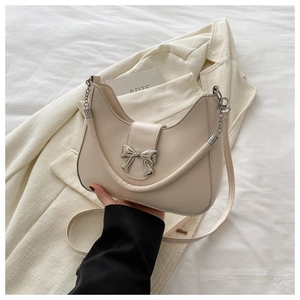 Détail du sac demi-lune crème avec boucle en nœud métallique argenté et bandoulière