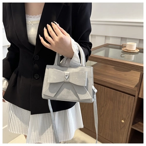 Détail du sac à main gris avec nœud et cristal sur modèle dans un cadre élégant
