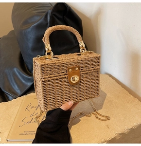 Detailed close-up of handmade straw bag featuring leather buckle and gold chain strap