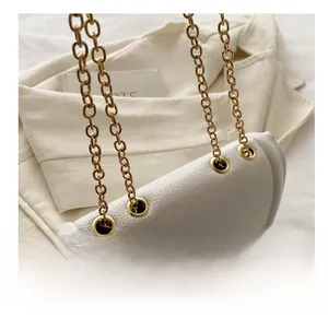 Détail d'un sac en cuir blanc texturé avec chaîne dorée et œillets métalliques chic