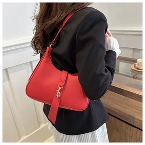 Detail of red hobo bag with gold carabiner buckle worn by model in casual chic style
