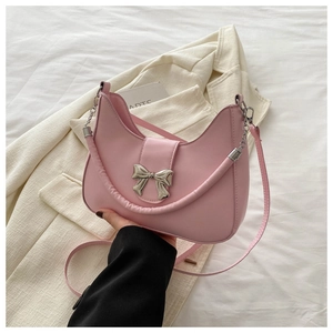 Détail d'un sac demi-lune rose avec nœud argenté et bandoulière en chaîne métallique