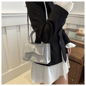 Détail du sac argenté à nœud avec diamant en cœur et surpiqûres élégantes