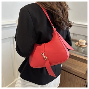 Detail of red crescent hobo bag with gold metal buckle on female model in a stylish setting