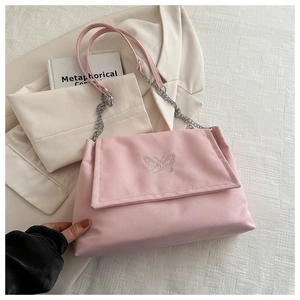 Détail d'un sac rose avec broderie papillon et chaîne argentée sur un blazer