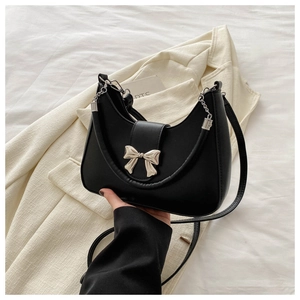 Vue détaillée du sac demi-lune noir avec nœud métallique argenté sur blazer beige