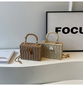 Detail of woven box-shaped handbags with gold metal turn-locks and chain straps