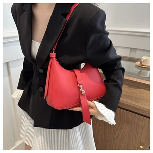 Detail view of red leather crescent hobo bag with a gold piston clasp on a model shoulder