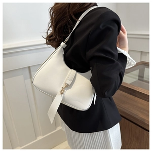 Detail of white half-moon shoulder bag with gold metal buckle on female model