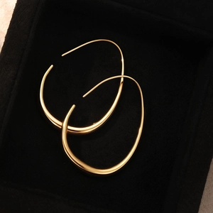 Boucles d'oreilles ovales irrégulières dorées dans un écrin à bijoux noir de luxe
