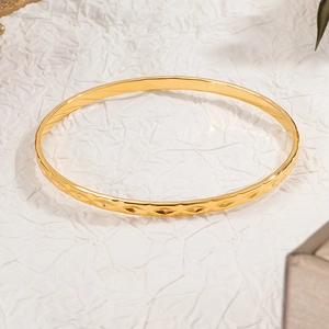 Elegant gold diamond-patterned titanium steel bangle on textured white background