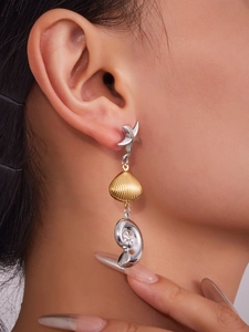 Macro view of ocean-themed triple drop earring with starfish, shell and nautilus charms