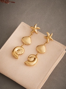Detailed view of 18k gold plated stainless steel starfish and seashell drop earrings