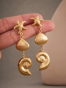 Macro shot of 18k gold plated stainless steel sea star and seashell drop earrings