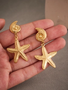 Detail of 18k gold plated stainless steel ocean conch and starfish drop earrings