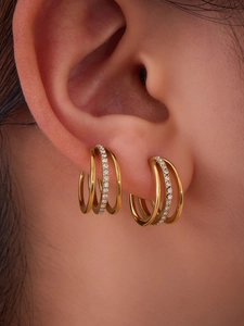 Vista macro de pendiente tipo cuff de tres capas dorado con circonitas pavé en el centro