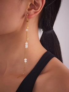 Close-up of star tassel earrings with white pearls and 18k gold chain on model