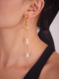 Close-up of dangling gold star tassel earrings with white pearls on a female model