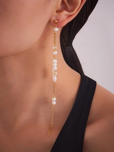 Close-up of star tassel earrings with white pearls and 18k gold-plated chains on a model
