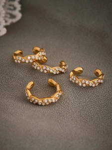 Detalle de cuatro pendientes ear cuff dorados con capas trenzadas y circonitas