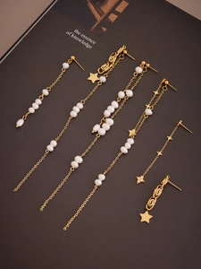 Detail shot of gold star tassel earrings with pearls and zircons on a dark background