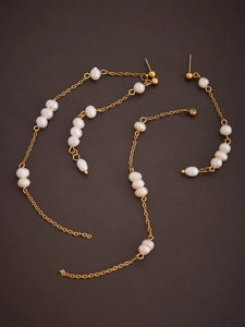Close-up of elegant long tassel earrings with white pearls on a gold chain