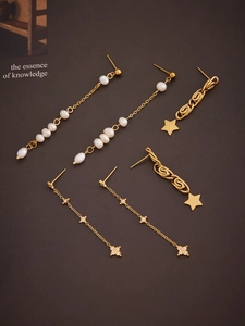 Close-up of three 18k gold star fringe earrings with pearls and sparkling zircon