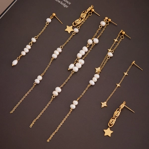 Gold-plated star earrings with tassel and pearls on vintage book background