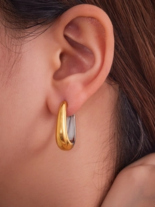 Gros plan de créoles en forme de U bicolores avec finition miroir or et argent sur l'oreille