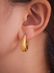 Gros plan d'une créole en U plaquée or polie sur l'oreille avec finition miroir éclatante