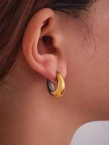Vue macro de boucles d'oreilles bicolores or et argent en forme de U sur l'oreille