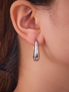 Gros plan de boucles d'oreilles goutte argentées polies sur un modèle au fini élégant