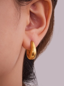 Gros plan sur des boucles d'oreilles créoles dorées en forme de goutte d'eau avec poli miroir