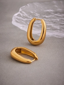 Détail de boucles d'oreilles en U plaquées or 18k polies sur une surface texturée