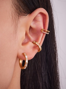 Vue macro des boucles d'oreilles plaquées or 18k avec zircons portées sur l'oreille