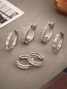 Détail macro de boucles d'oreilles argentées géométriques avec zircons sur fond texturé