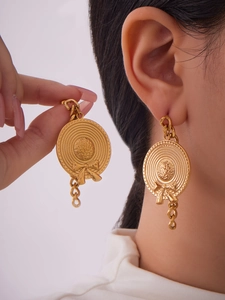 Macro view of gold-plated stainless steel bow-knot straw hat drop earrings with chains
