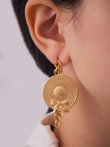 Detailed view of vintage gold bow hat charm earring with a chain drop on a model