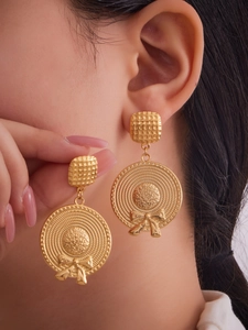 Close-up of 18k gold plated bow hat earrings with grid texture on a model