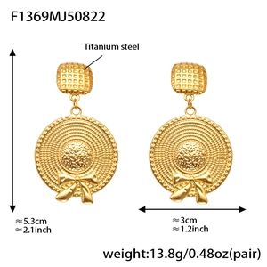 Detailed view of titanium steel earrings with gold finish, bow and hat charms