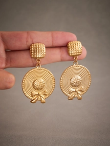 Detailed view of gold bow-knot straw hat earrings with woven textures on polished finish