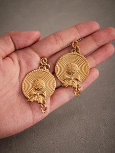 Detail of 18k gold plated French straw hat earrings with bow and woven texture