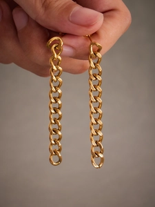 Detailed view of long gold-plated curb chain earrings held by hand to show size