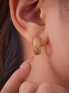Nahaufnahme der goldenen Gitterohrringe mit funkelnden Zirkonia am Ohr eines Models