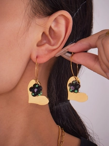 Gros plan d'un mannequin portant des boucles d'oreilles cœur dorées et fleur