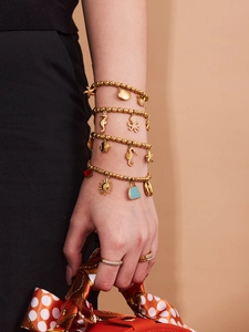 Detail of gold ocean-themed charm bracelets with octopus and starfish on a model wrist