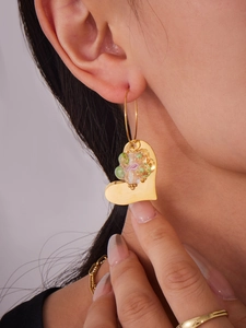 Gros plan de la boucle d'oreille cœur doré avec perle de fleur en résine portée