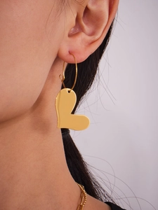 Gros plan d'un mannequin portant des boucles d'oreilles cœur en or poli style moderne