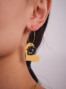 Gros plan de boucles d'oreilles cœur en or avec motif floral porté par un mannequin