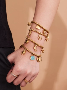Detail of gold beaded bracelet set with ocean starfish and seahorse charms on a wrist